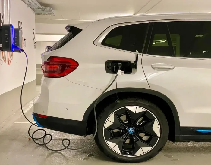 Un coche eléctrico blanco cargando en un punto de recarga en un garaje